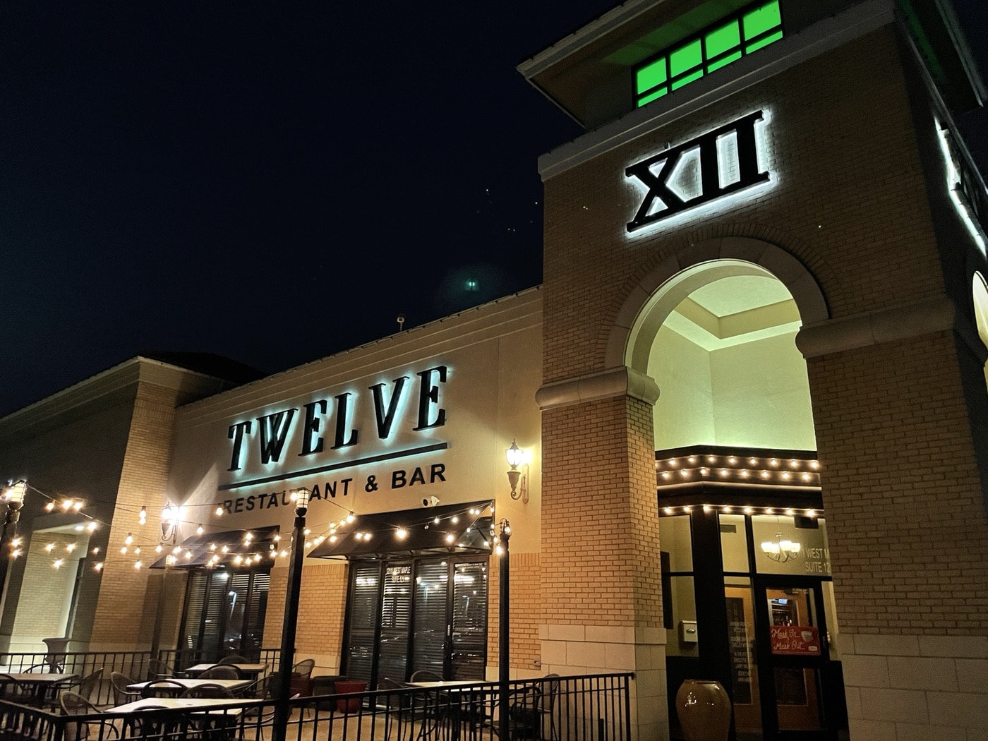 A beautifully lit restaurant exterior in Wichita, KS, featuring fresh commercial paint and elegant architectural details. The bold signage and warm lighting create an inviting atmosphere.