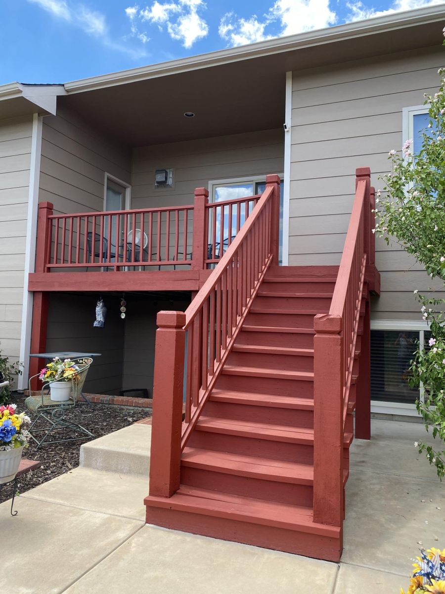 A red-painted wooden deck and stairs on a Winfield, KS home, finished by professional painters.