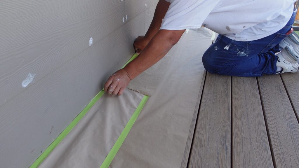 A painter in Winfield, KS carefully masking siding during prep work for an exterior painting project.