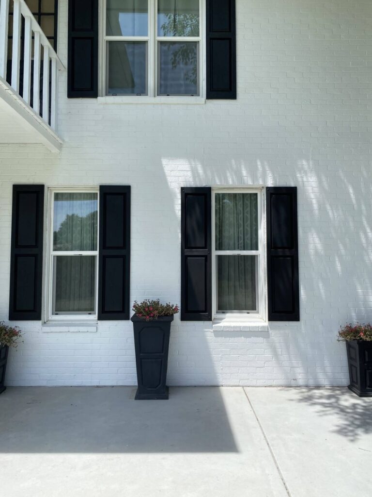 A Wellington, KS home with a freshly painted white brick exterior and bold black shutters.