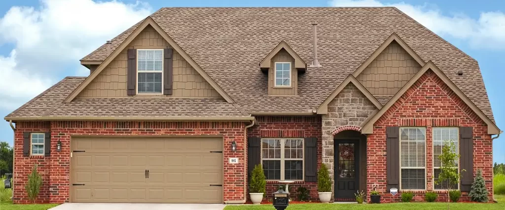 elegant brick house with gabled roof beige garage and manicured lawn