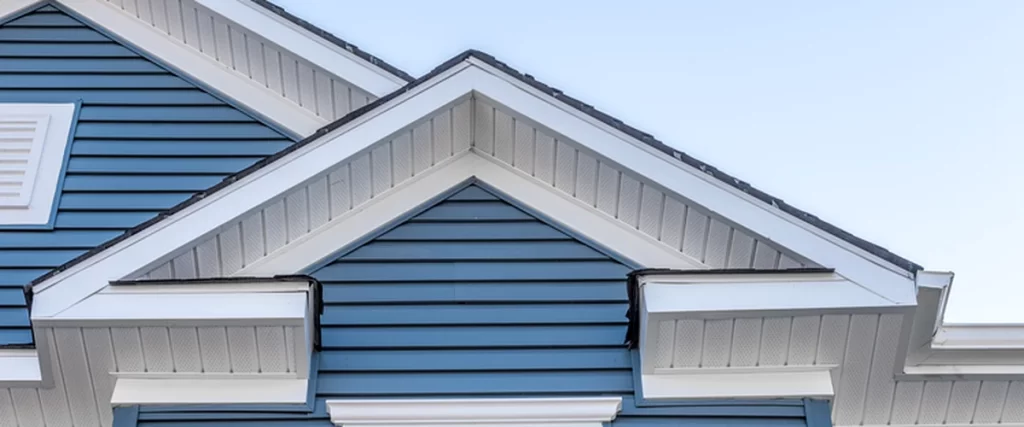 painting expert exterior painting of a house featuring blue vinyl siding with white trim and soffits showcasing professional contractor quality workmanship against a clear