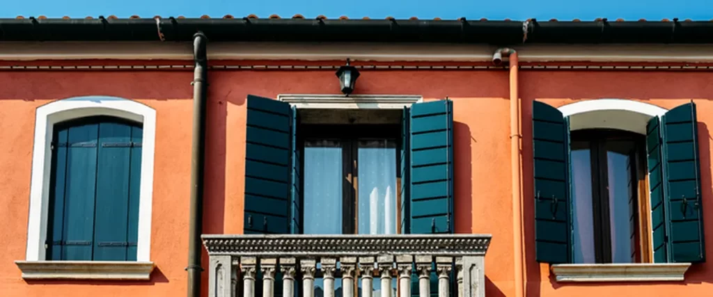 terracota stucco facade with blue shutters and a stone balustrade balcony professional exterior painting and architectural renovation