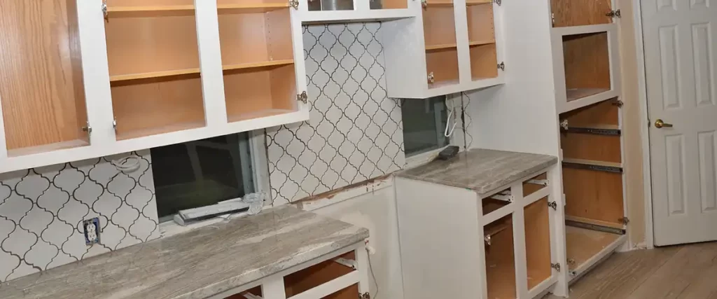Kitchen cabinets being prepped for painting with doors removed