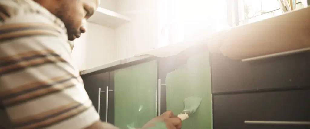 Man painting green kitchen cabinet doors