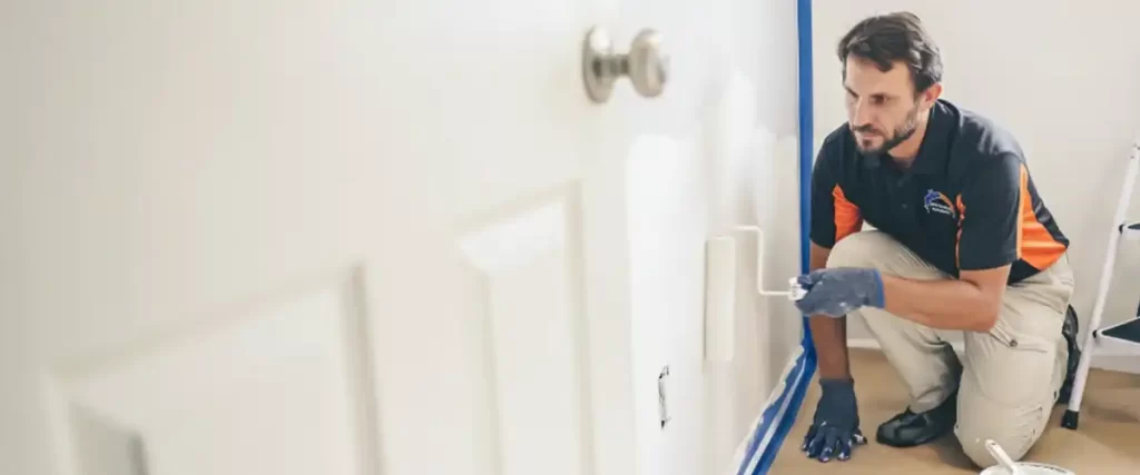 Painter from Roll Call Painting using a roller to apply fresh white paint on an interior wall

