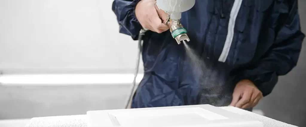 Painter spraying cabinet door with white paint finish